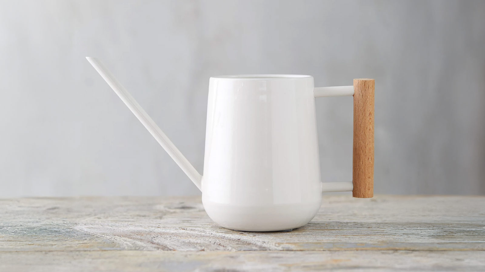 White metal watering can with a sculptural beech‑wood handle — a functional, stylish gift for design lovers.