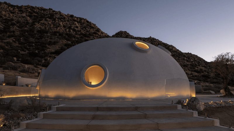 Sculptural concrete dome house in California’s High Desert, designed by Anastasiya Dudik, with curved monolithic exterior, saltwater pool, and minimalist brutalist interior built from concrete, stone, and plaster.
