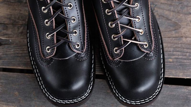 Nick's x Carl Murawski Blackwood 8 " logger boots in overdyed black English bridle leather, showing an emerging brown patina, brass hardware, and Supergrip soles.