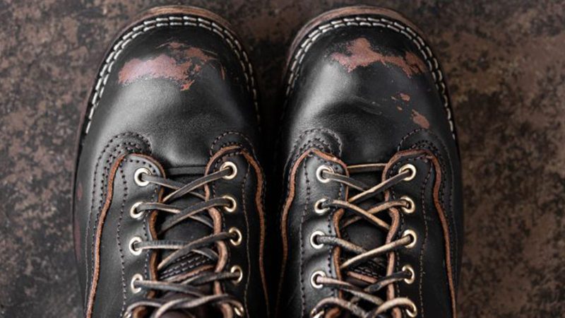 Nick's x Carl Murawski Blackwood 8 " logger boots in overdyed black English bridle leather, showing an emerging brown patina, brass hardware, and Supergrip soles.