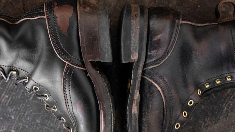 Nick's x Carl Murawski Blackwood 8 " logger boots in overdyed black English bridle leather, showing an emerging brown patina, brass hardware, and Supergrip soles.