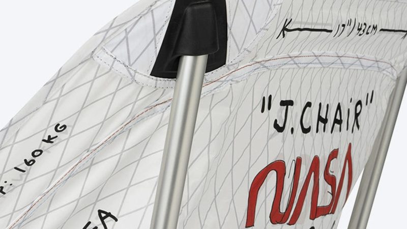 Tom Sachs J.Chair by Helinox features a raw DAC aluminum frame, NASA-inspired typography, and Vibram feet, blending industrial design with functional outdoor art.