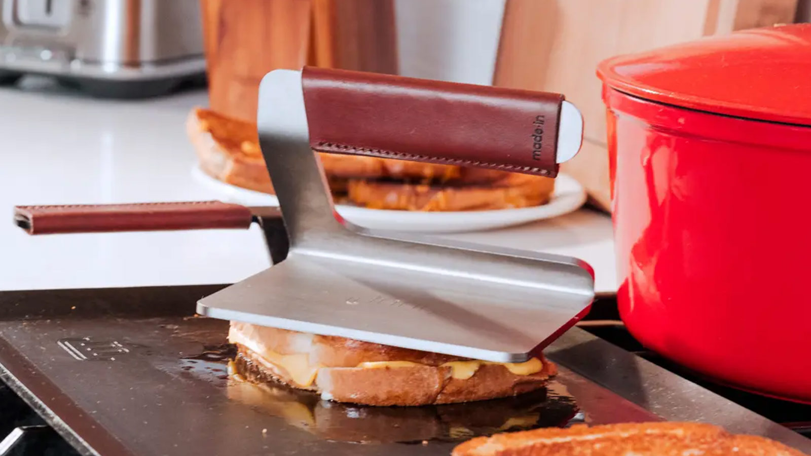 Made In stainless steel grill press with leather-wrapped handle—heavy-duty contender in the best grilling tools for crispy sears.