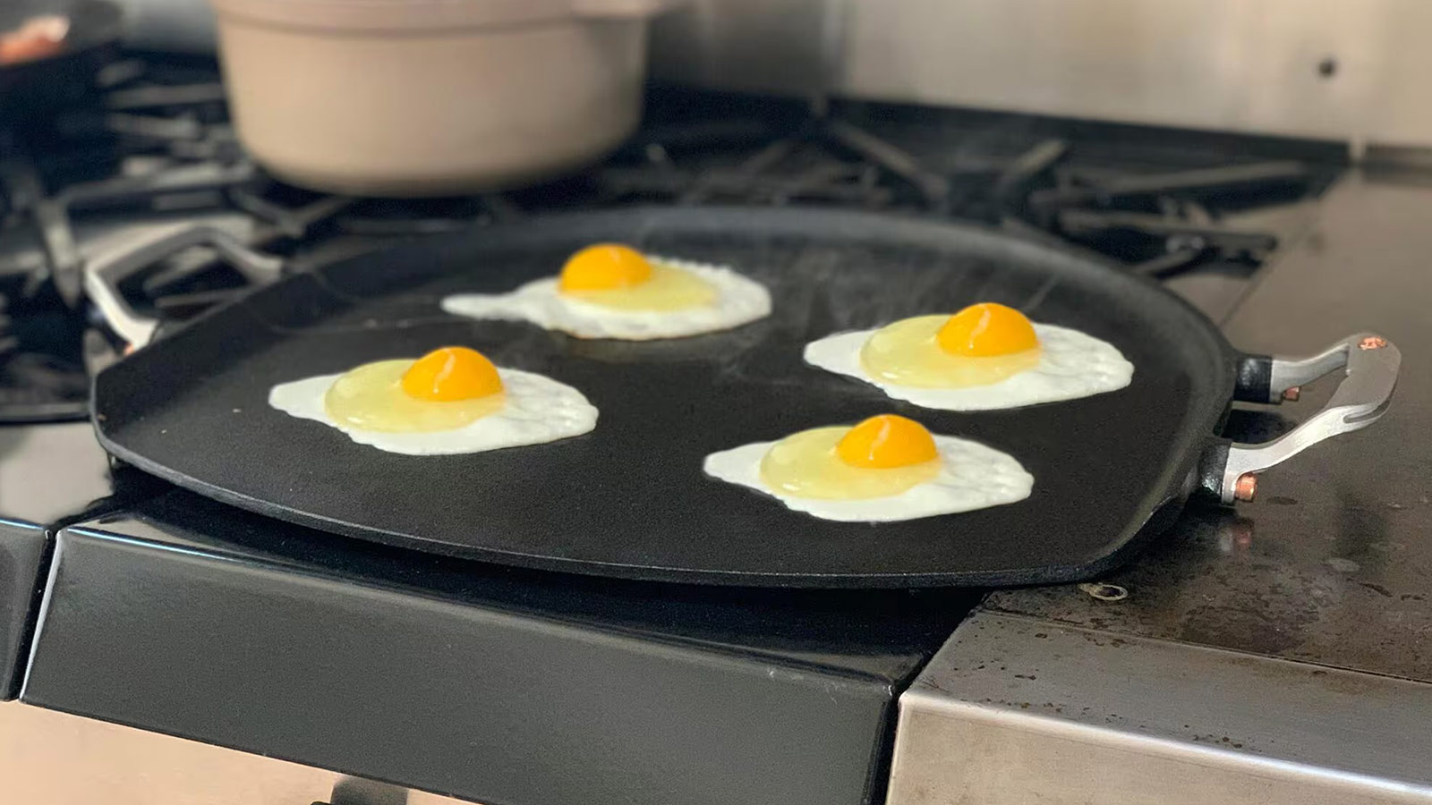 Cast iron pizza iron on stovetop with eggs cooking—multi-use pan that deserves a spot on the best grilling tools list.