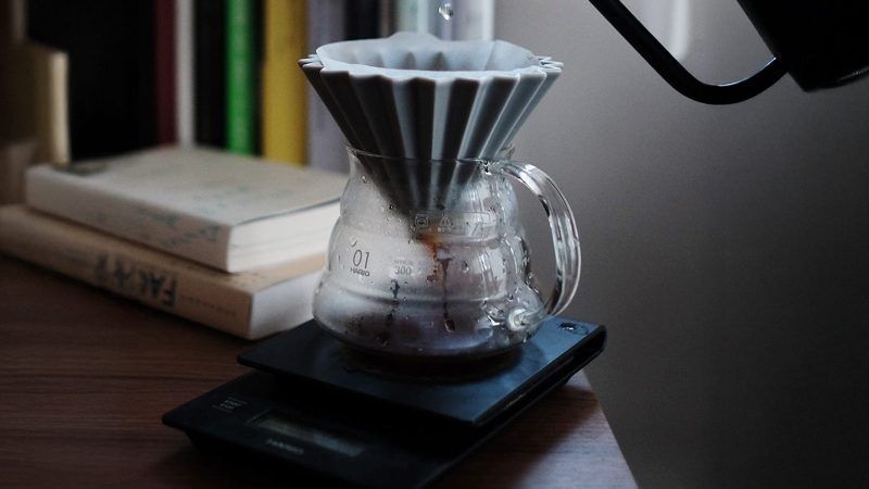 Origami coffee dripper and scale brewing pour-over as part of a mindful morning routine for men.