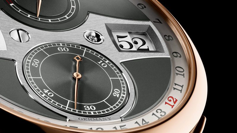 A. Lange & Söhne Zeitwerk Date in 18k pink gold with slate-gray dial, features a digital time display, outer date ring, and in-house calibre L043.8 movement visible through a sapphire caseback.