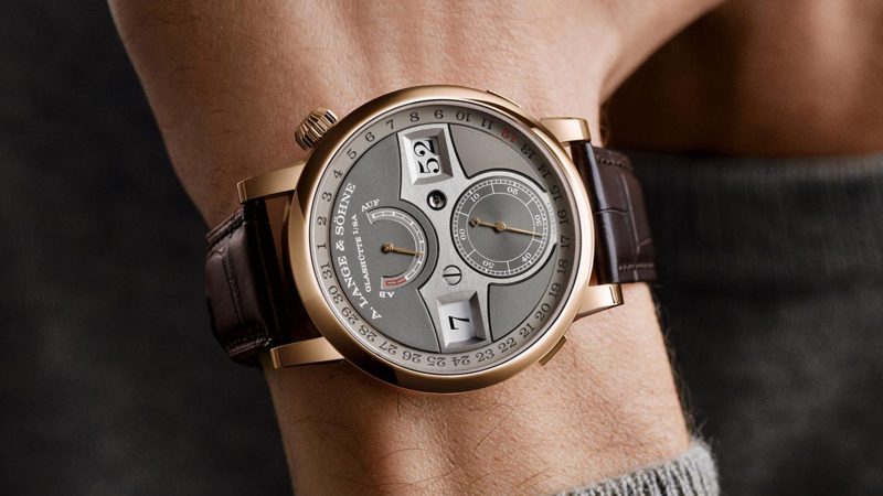 A. Lange & Söhne Zeitwerk Date in 18k pink gold with slate-gray dial, features a digital time display, outer date ring, and in-house calibre L043.8 movement visible through a sapphire caseback.