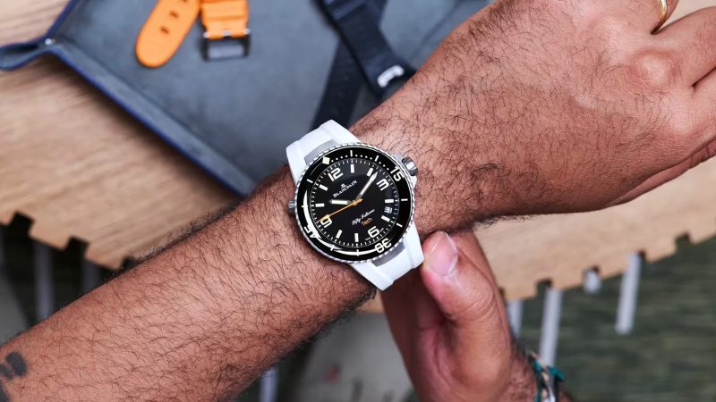 Blancpain Fifty Fathoms Tech 5029 dive watch with brushed titanium case, black dial, ceramic bezel, and bold orange rubber strap—combining professional diving specs with refined lifestyle appeal.
