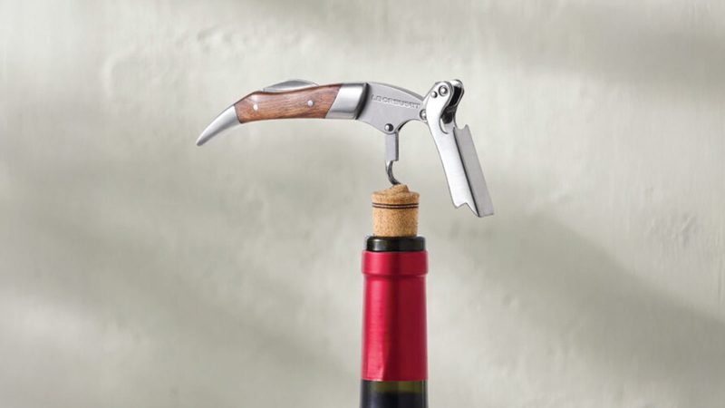 A close up on a bottle opener opening a bottle of wine