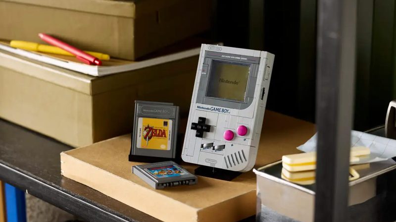 LEGO Game Boy model kit with 421 pieces shown assembled, featuring accurate buttons, interchangeable Zelda and Mario cartridges, lenticular screen options, and a custom display stand—perfect for retro gaming fans and collectors.
