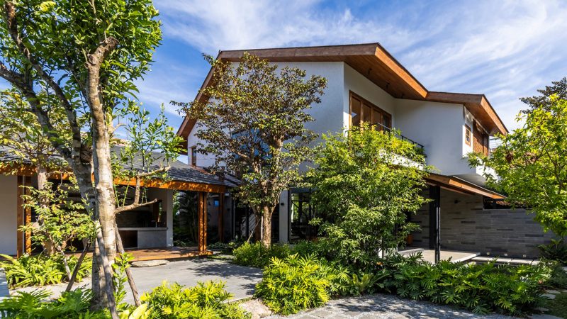 Exterior and interior views of OM House by AN NAM Architecture, showcasing sustainable sandstone walls, verdant gardens, and minimalist modern Vietnamese architecture designed for tranquility.