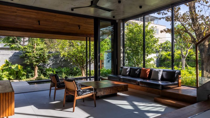 Exterior and interior views of OM House by AN NAM Architecture, showcasing sustainable sandstone walls, verdant gardens, and minimalist modern Vietnamese architecture designed for tranquility.