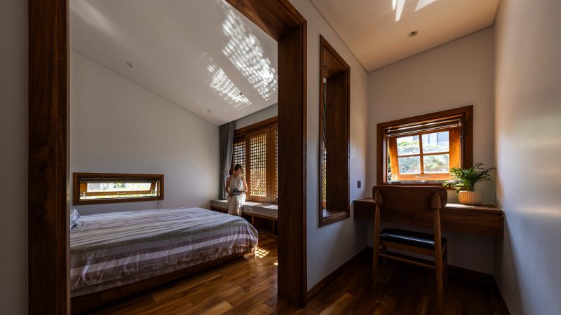 Exterior and interior views of OM House by AN NAM Architecture, showcasing sustainable sandstone walls, verdant gardens, and minimalist modern Vietnamese architecture designed for tranquility.