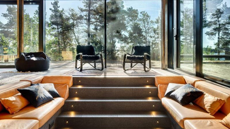 Scandinavian-off‑grid island retreat: Corten-steel homes, sauna, sunken terrace, nestled pine & rugged Baltic shoreline.