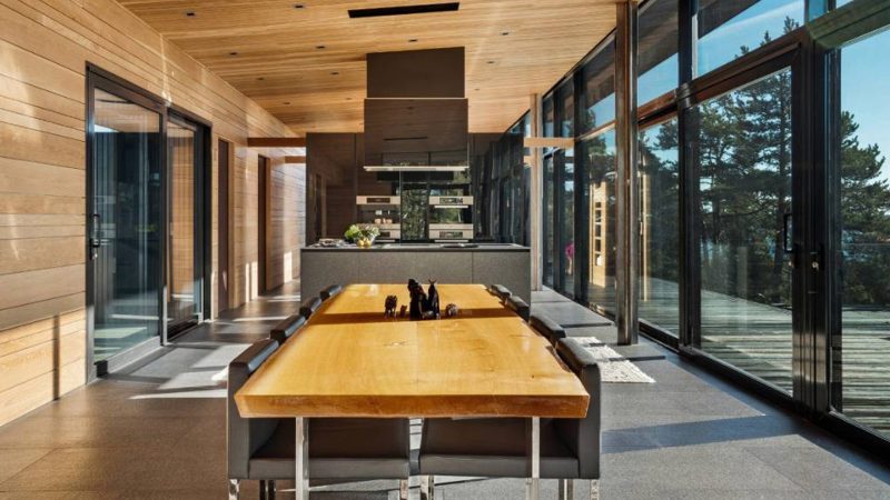 Scandinavian-off‑grid island retreat: Corten-steel homes, sauna, sunken terrace, nestled pine & rugged Baltic shoreline.