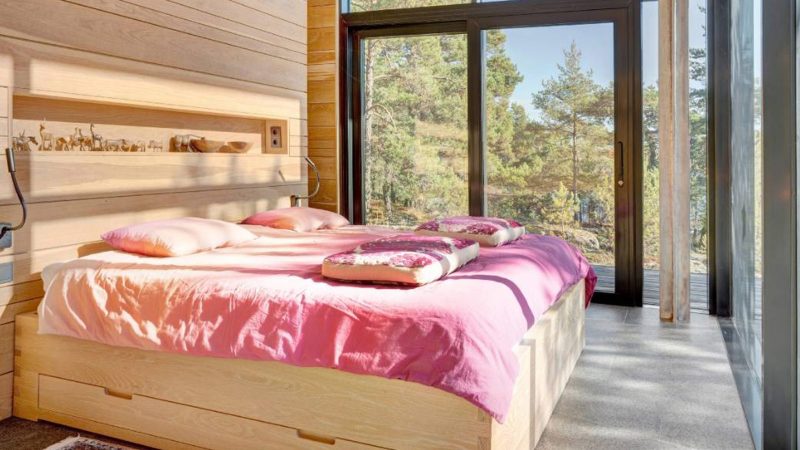 Scandinavian-off‑grid island retreat: Corten-steel homes, sauna, sunken terrace, nestled pine & rugged Baltic shoreline.