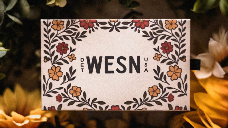 The WESN Grow North Microblade features bright floral G10 scales, a titanium back handle, and antique brass coin packaging—limited to 200 units for summer 2025.