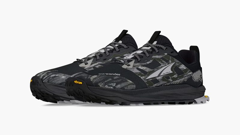 Altra x and wander Lone Peak 9+ trail shoe with alpine graphic overlays, Vibram Megagrip outsole, zero-drop platform, and bold orange and black colorways.