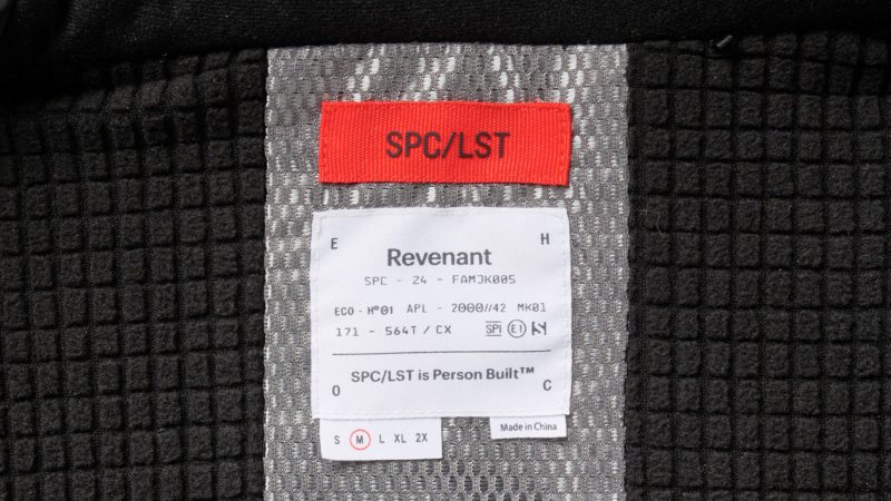 SPC/LST Revenant Weatherproof Parka in black with oversized fit and drop-tail hem, showcasing recycled materials, PrimaLoft insulation, and technical weatherproof design.