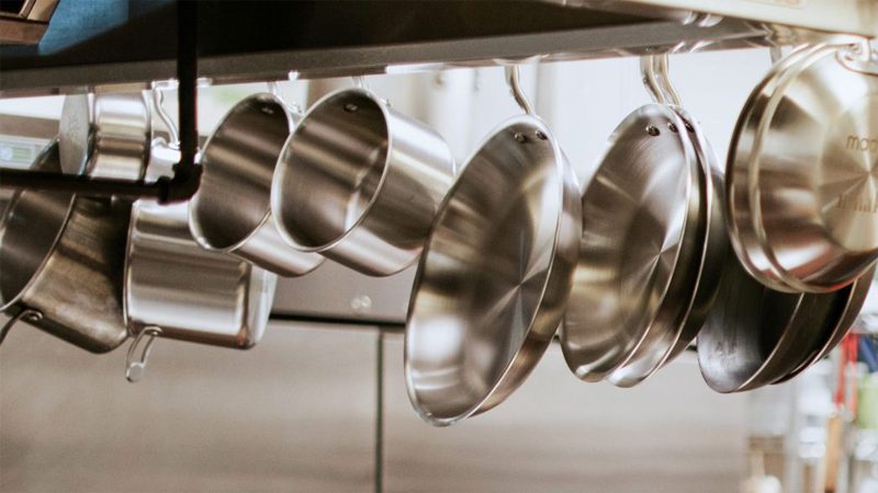 Sleek stainless steel cookware hanging in a modern kitchen – the ultimate modern home essentials for men who cook with style.