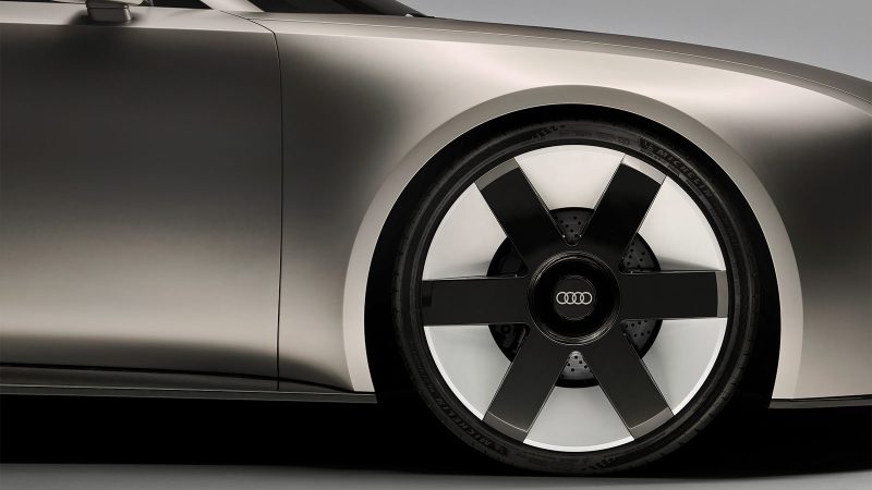 The Audi Concept C is an all-electric two-seat roadster featuring a vertical frame grille, a titanium finish, and a retractable hardtop, showcasing Audi’s next-generation design.