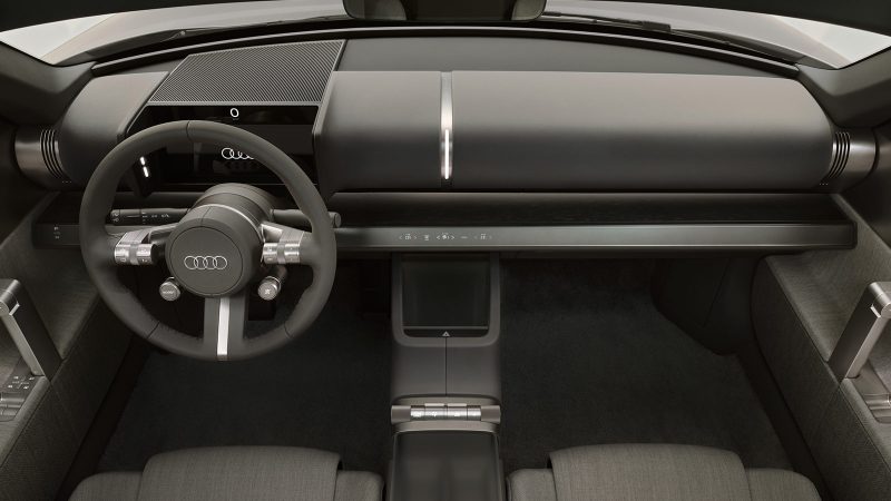 The Audi Concept C is an all-electric two-seat roadster featuring a vertical frame grille, a titanium finish, and a retractable hardtop, showcasing Audi’s next-generation design.
