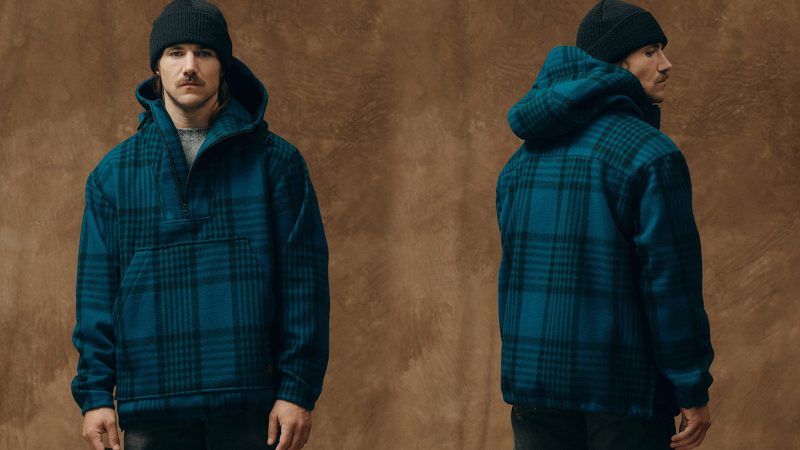 Filson’s Mackinaw Wool Anorak features durable 100% wool construction, adjustable hood and cuffs, a kangaroo pocket, and a quarter-zip front for versatile cold-weather performance.