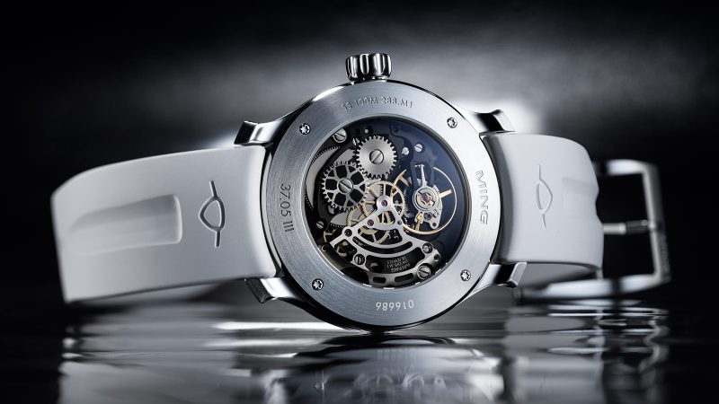 The MING 37.05 Lunatic watch has a sapphire dial, a luminous moonphase, a stainless steel 38mm case, and a white FKM rubber strap.