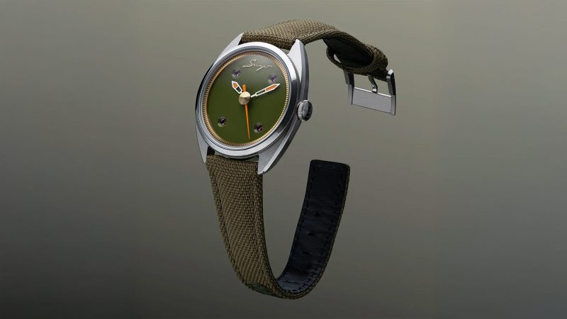 The Singer Caballero watch with stainless steel C-shaped case, green, black, or blue lacquered dial, inset rubies, and signature orange-lumed hands on a textile or leather strap.