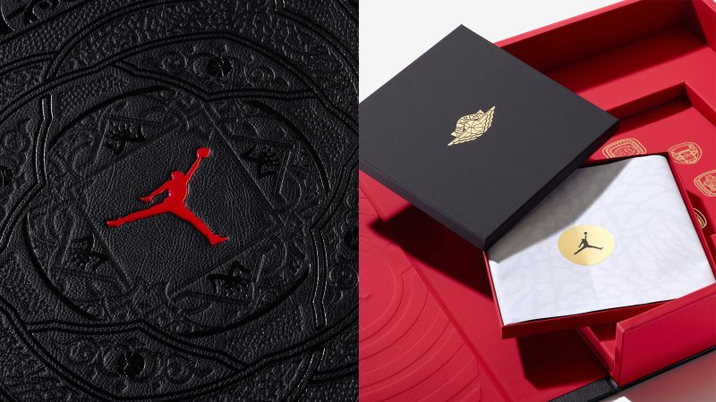 A deluxe edition book titled ‘Air Jordan: The Ultimate Collection’ by Assouline, encased in an ornate black leather clamshell box embossed with Baroque motifs, with a red ribbon and gold medallion bookmark visible.