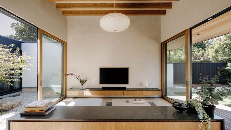 Cupertino Courtyard House exterior by SHED Architecture, featuring white stucco walls and charred-wood upper volume surrounded by lush courtyards.