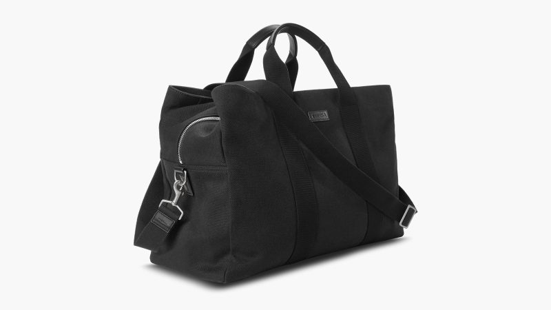 Shinola’s Runwell Canvas Duffle Bag in black canvas with leather trim, matte nickel hardware, and a TSA-approved carry-on design.