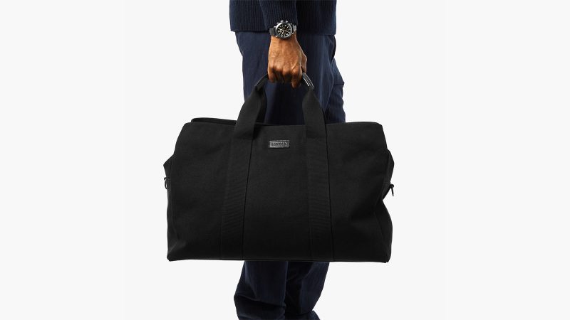 Shinola’s Runwell Canvas Duffle Bag in black canvas with leather trim, matte nickel hardware, and a TSA-approved carry-on design.