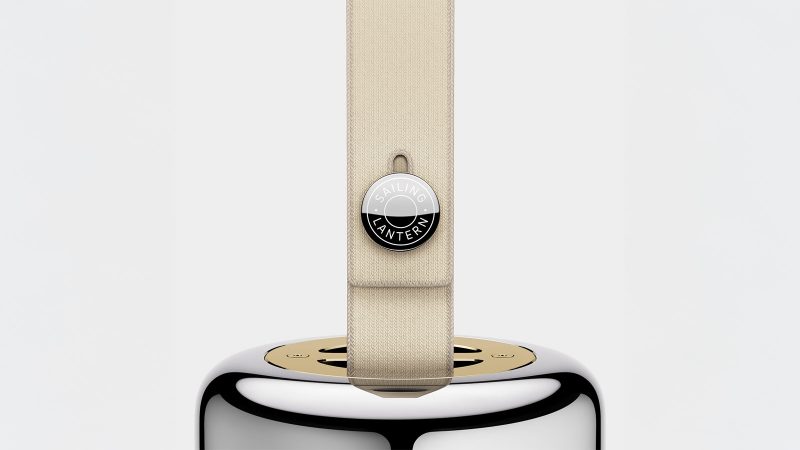 LoveFrom x BALMUDA Sailing Lantern in polished stainless steel with gold accents, suspended by a woven marine-grade lanyard.