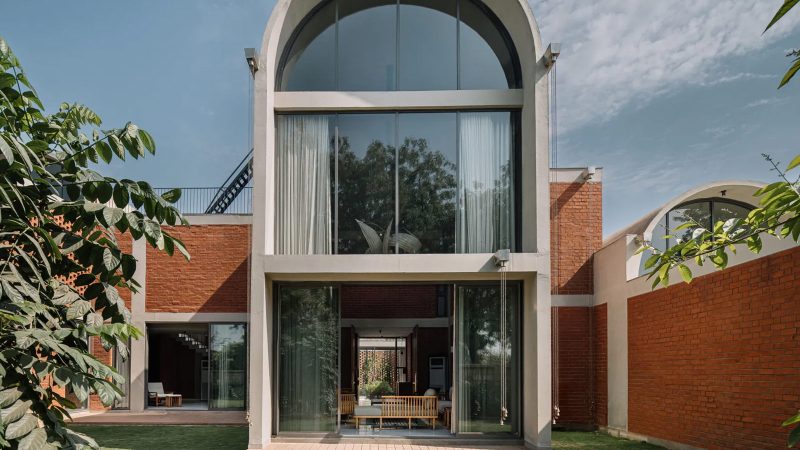 The Teen Vaults House features concrete vaults, exposed brick walls, and a lush green courtyard set beneath Ahmedabad’s tranquil skies.