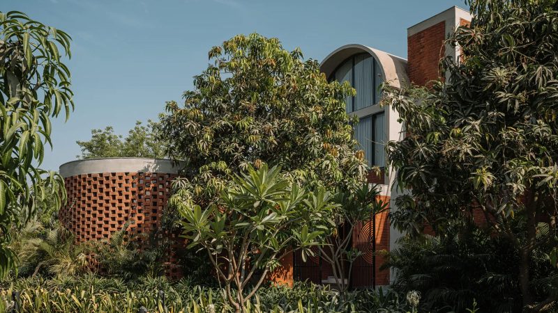The Teen Vaults House features concrete vaults, exposed brick walls, and a lush green courtyard set beneath Ahmedabad’s tranquil skies.