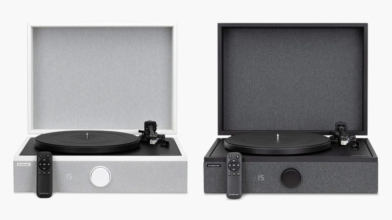 High-end all-in-one record player system by Andover Audio: a sleek black turntable with built-in amp and speakers, hard-cover lid open, vinyl spinning, minimalist aesthetic.