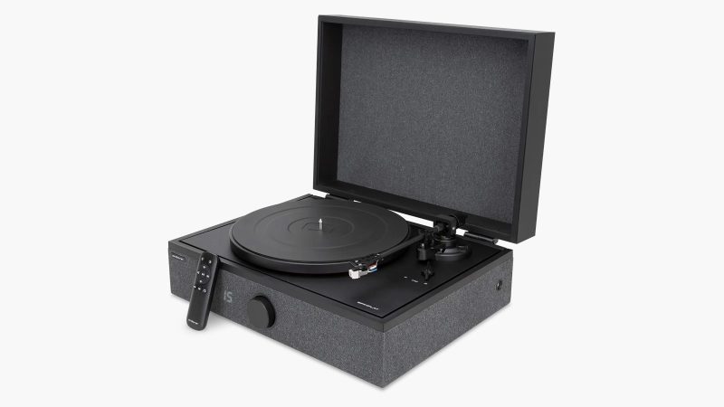 High-end all-in-one record player system by Andover Audio: a sleek black turntable with built-in amp and speakers, hard-cover lid open, vinyl spinning, minimalist aesthetic.