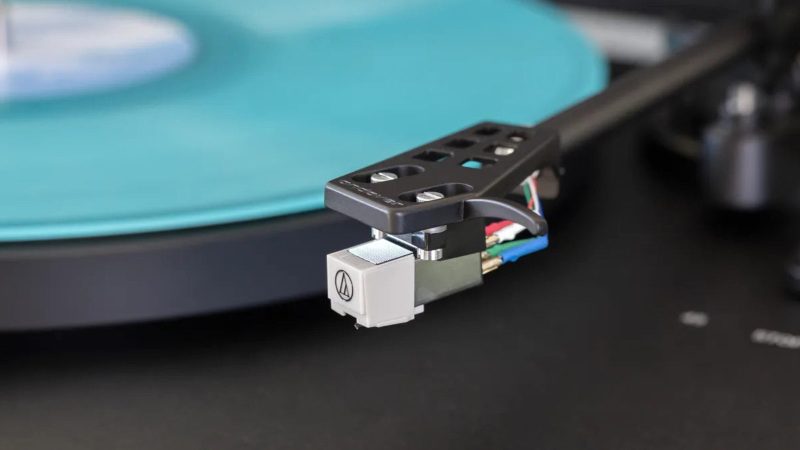 High-end all-in-one record player system by Andover Audio: a sleek black turntable with built-in amp and speakers, hard-cover lid open, vinyl spinning, minimalist aesthetic.