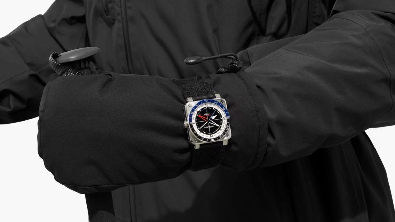 The Bell & Ross BR-03 GMT Compass watch with a square steel case, a black dial, a dual-color 24-hour bezel, and a red GMT hand.