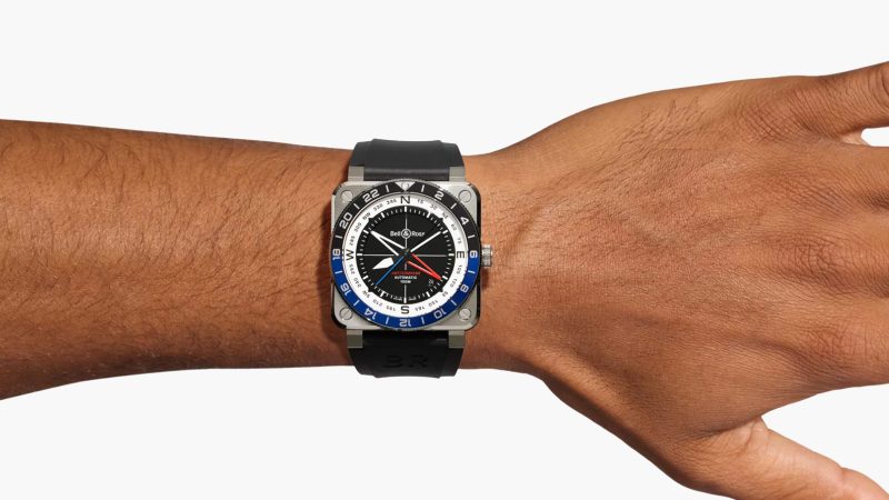 The Bell & Ross BR-03 GMT Compass watch with a square steel case, a black dial, a dual-color 24-hour bezel, and a red GMT hand.