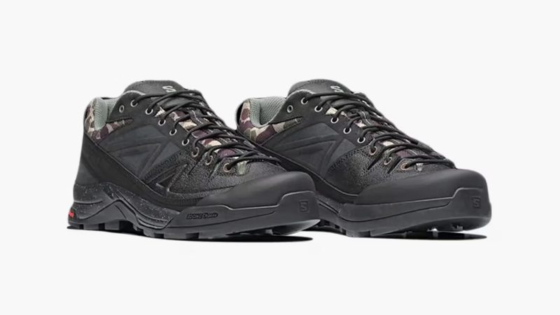 The Carhartt WIP x Salomon X-ALP is a black leather and synthetic trail sneaker with duck camo collar, rubber mudguard, and Utilitarian workwear flair.