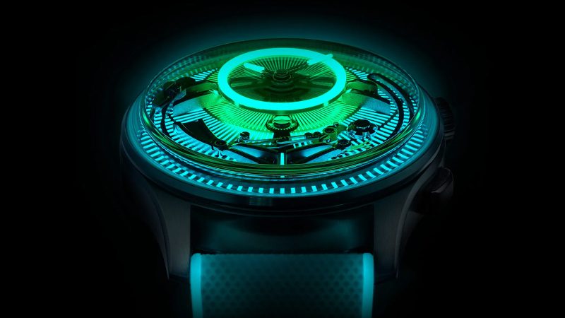 Christopher Ward’s C1 Bel Canto Lumière glowing titanium watch with luminous dial, blue accents, and white Super-LumiNova strap.