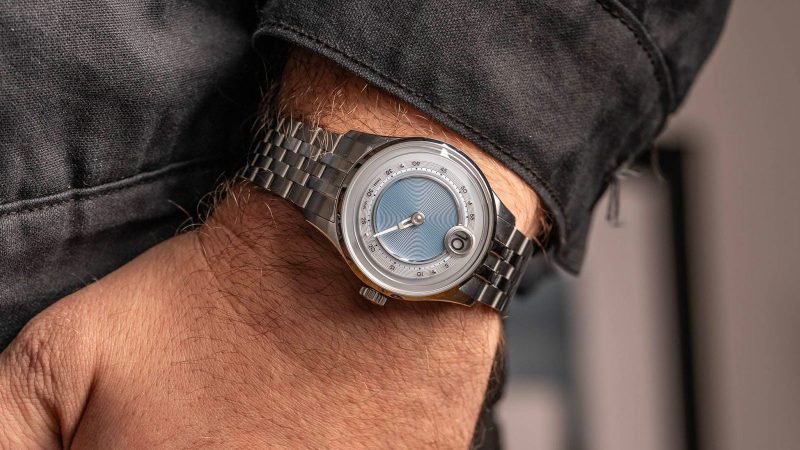 The Christopher Ward C1 Jump Hour Mk V watch with a glowing sapphire dial ring and jump hour display in Noon Blue.