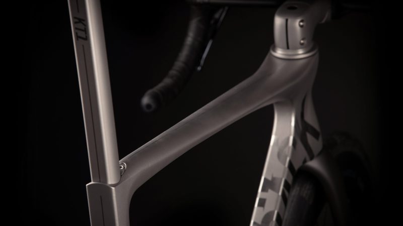 A sleek matte-titanium J.Laverack Speedform road bike with 3-D printed frame sections, internal cable routing, and aerodynamic tubing against a dark studio background.