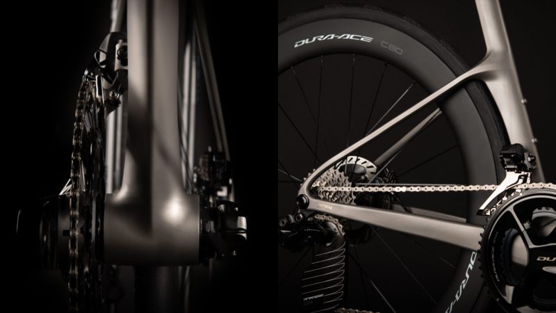 A sleek matte-titanium J.Laverack Speedform road bike with 3-D printed frame sections, internal cable routing, and aerodynamic tubing against a dark studio background.