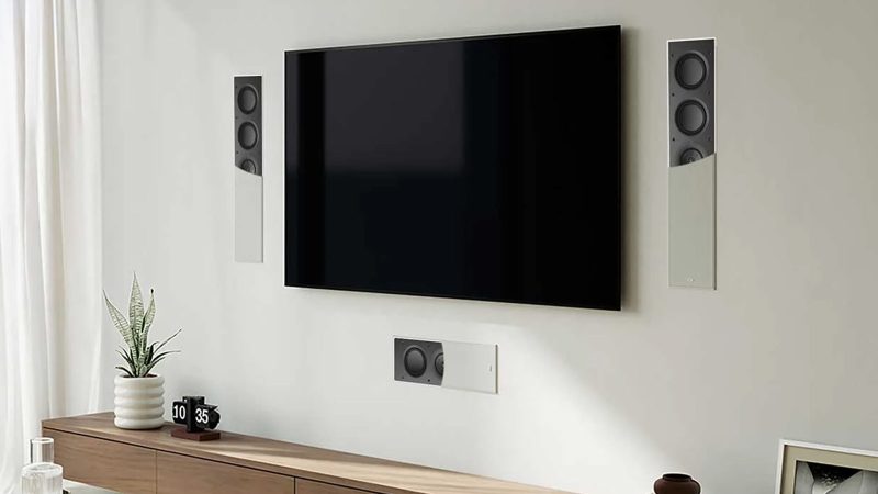 A sleek in-wall KEF architectural speaker mounted flush in drywall, showing the ultra-thin bezel and paintable grille blending with modern interior.