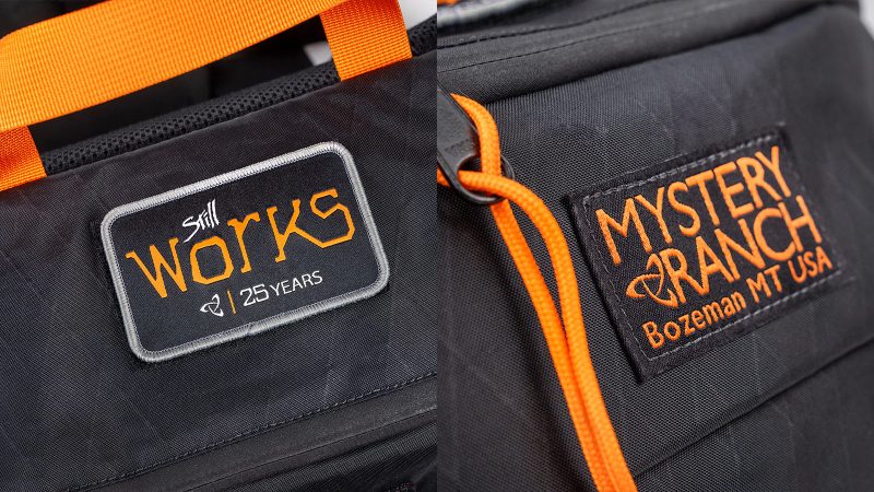 Mystery Ranch Hip Monkey 25 Legacy Edition waist pack in X-Pac sailcloth with orange trim, commemorative patch, and adjustable hip belt.