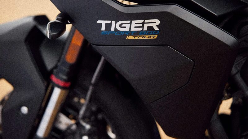 The 2026 Triumph Tiger Sport 800 Tour motorcycle with panniers, top case, 798cc triple engine, touring accessories, heated grips, comfort seat, TPMS, and Showa suspension.