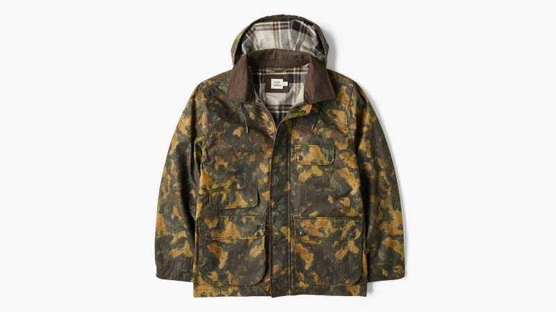 Flint and Tinder’s Flannel-Lined Waxed Hudson Jacket in limited-edition kelp camo featuring Halley Stevensons waxed cotton canvas, flannel lining, removable hood, moleskin trim, and multiple utility pockets.